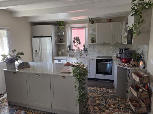 Cuisine à Saint-Jean-de-Lier avec façades beige mat, granit Colonial White, îlot central et équipements haut de gamme.